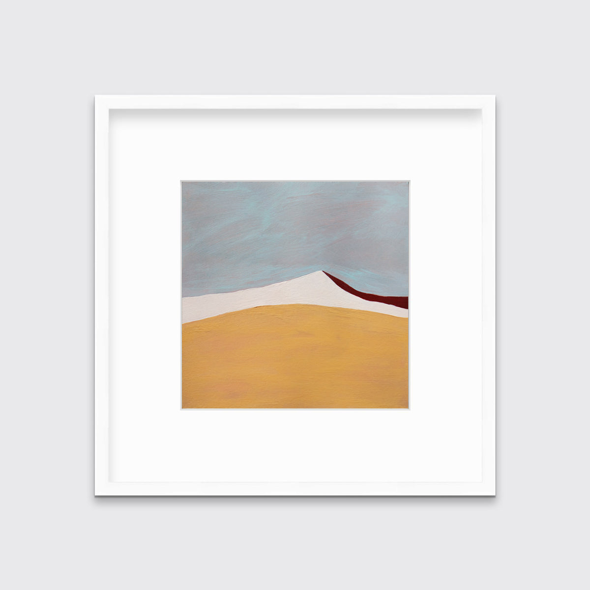 A dark yellow, white, dark red and slate blue abstract landscape print in a white frame with a mat hangs on a white wall.