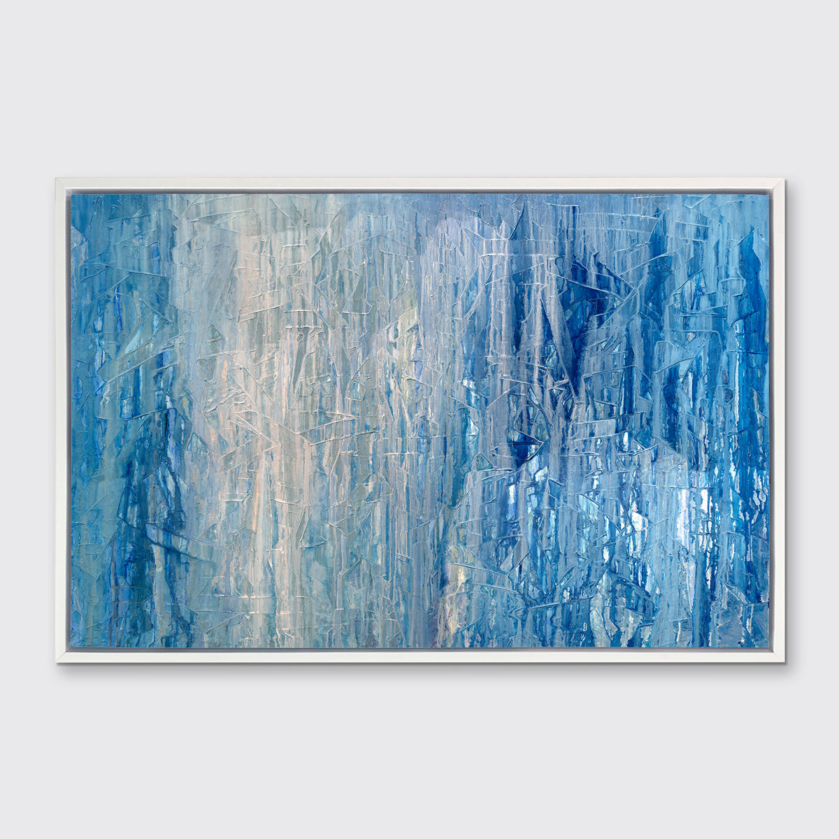 A blue, white and grey abstract print in a white floater frame hangs on a white wall.