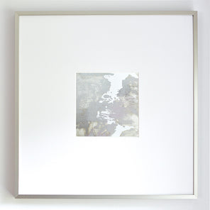 A small grey and silver painted art mirror in a silver frame with a large white mat hangs on a white wall.