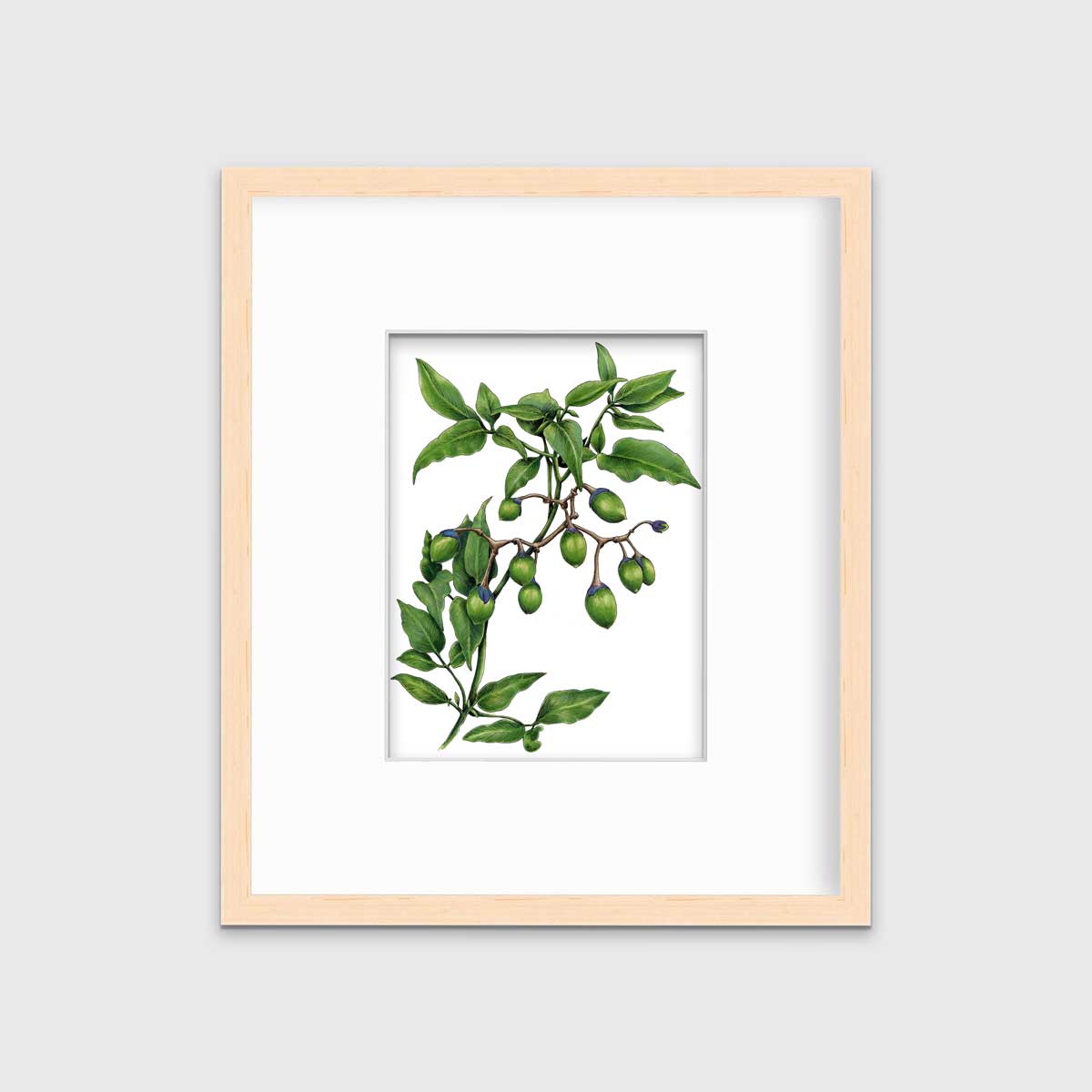 A green plant print in a natural wood frame with a mat hangs on a white wall.