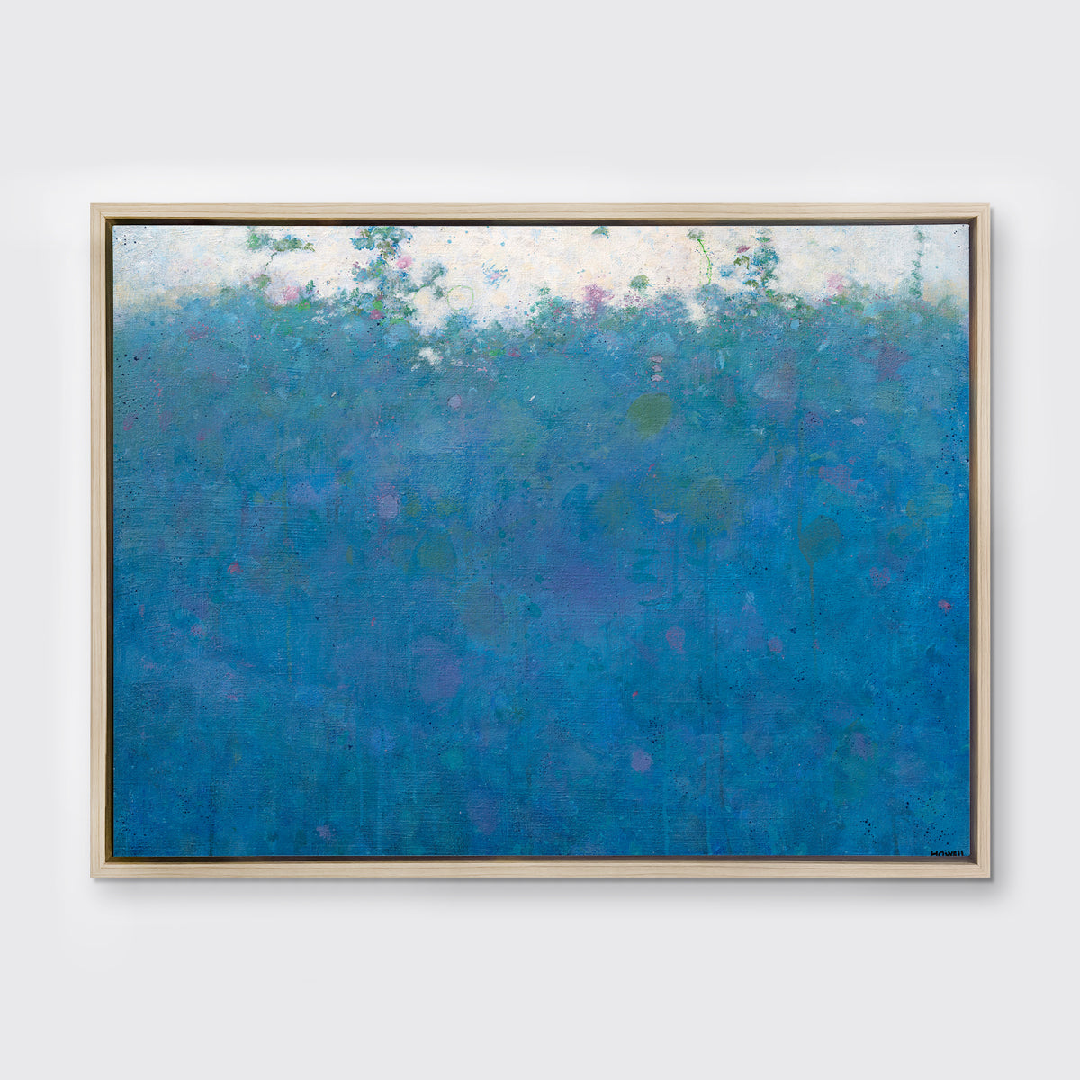 A blue, green, pink and white abstract landscape print in an oak wood floater frame hangs on a white wall.