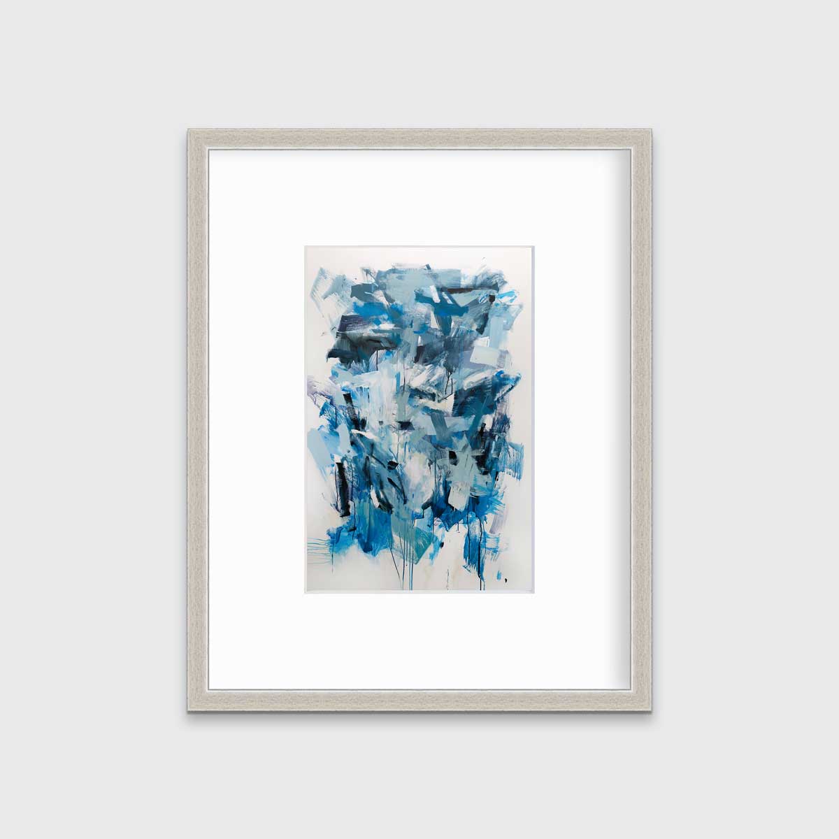 A blue, teal and white abstract print in a silver frame with a mat hangs on a white wall.
