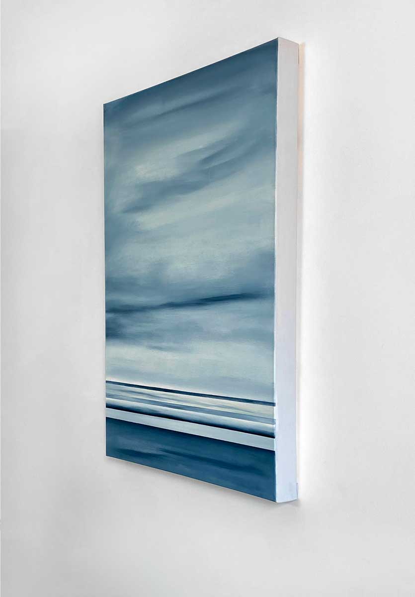 A right side-angle view of a blue and grey abstract geometric painting hanging on a white wall.