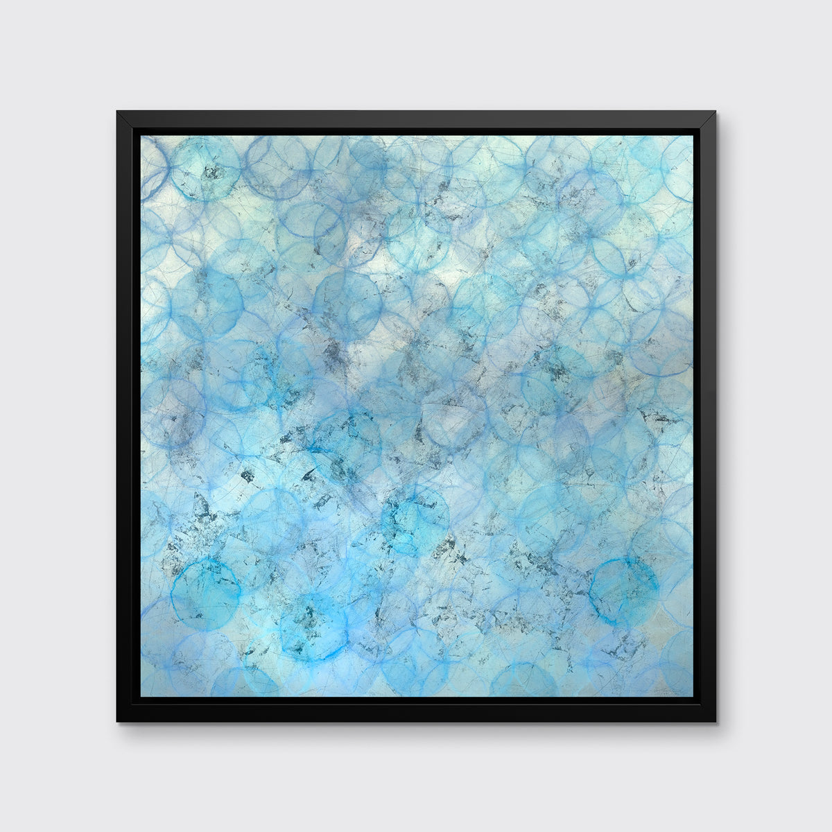 A blue and silver abstract circle print in a black floater frame hangs on a white wall.