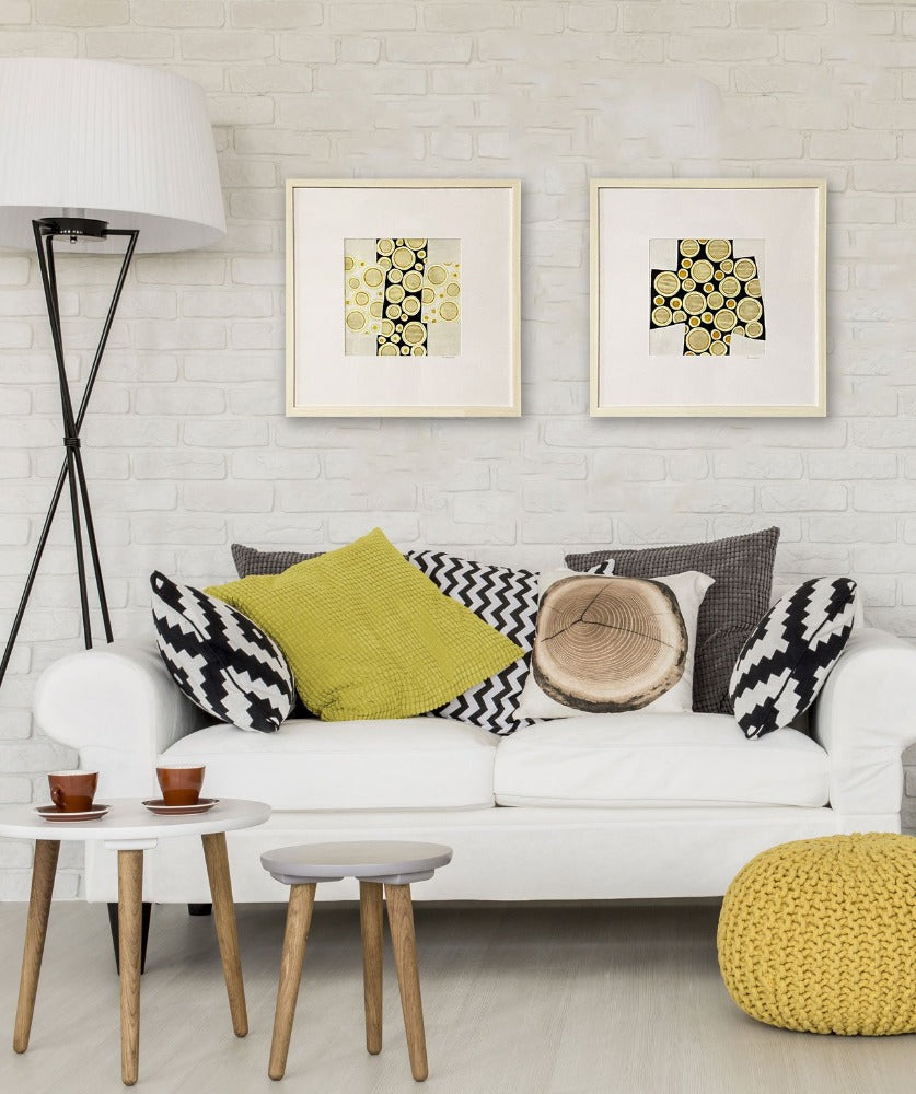 Bubbles #1 framed painting, hanging on the wall next to Bubbles #2 above a white couch with black and yellow pillows.