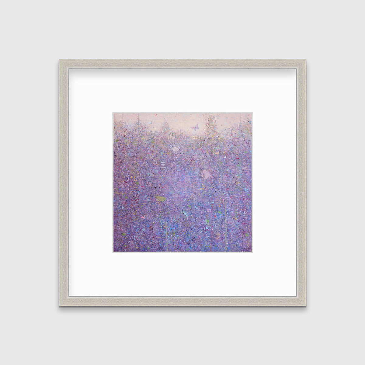 A pink abstract landscape in a silver frame with a mat hangs on a white wall.
