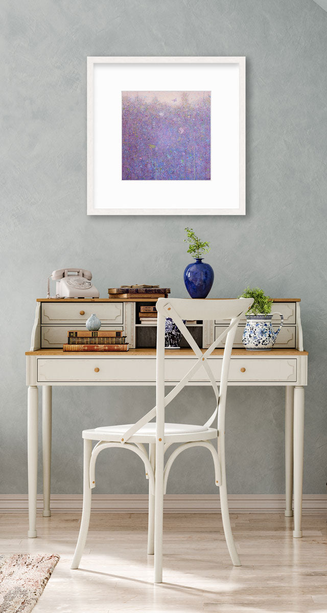 A pink abstract landscape in a whitewashed frame with a mat hangs on a light blue textured wall above a two-tiered white desk with a rotary phone, stacks of books, vases with greenery and a white chair.