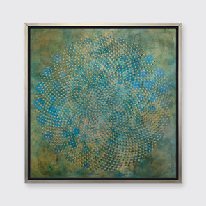 A green, blue and gold overlapping circle print in a silver floater frame hangs on a white wall.