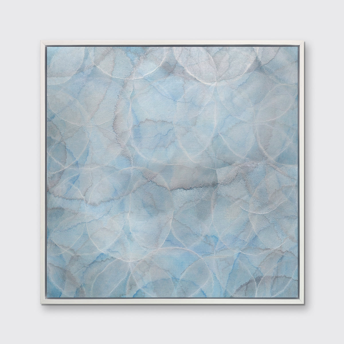 A light blue abstract overlapping circle print in a white floater frame hangs on a white wall.
