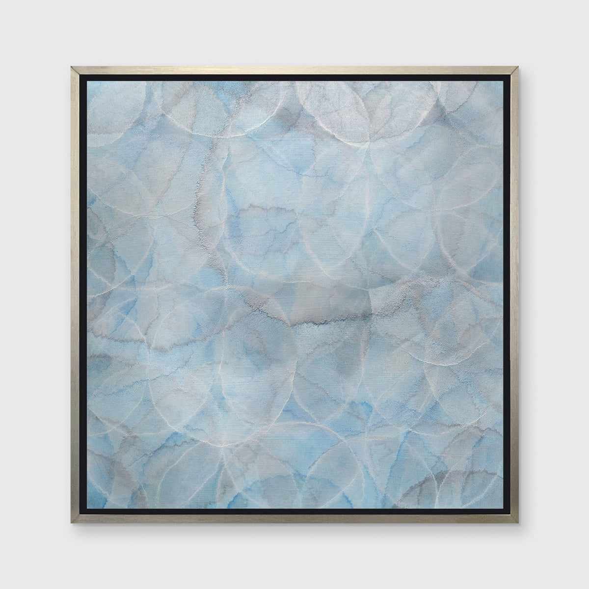A light blue abstract overlapping circle print in a silver floater frame hangs on a white wall.
