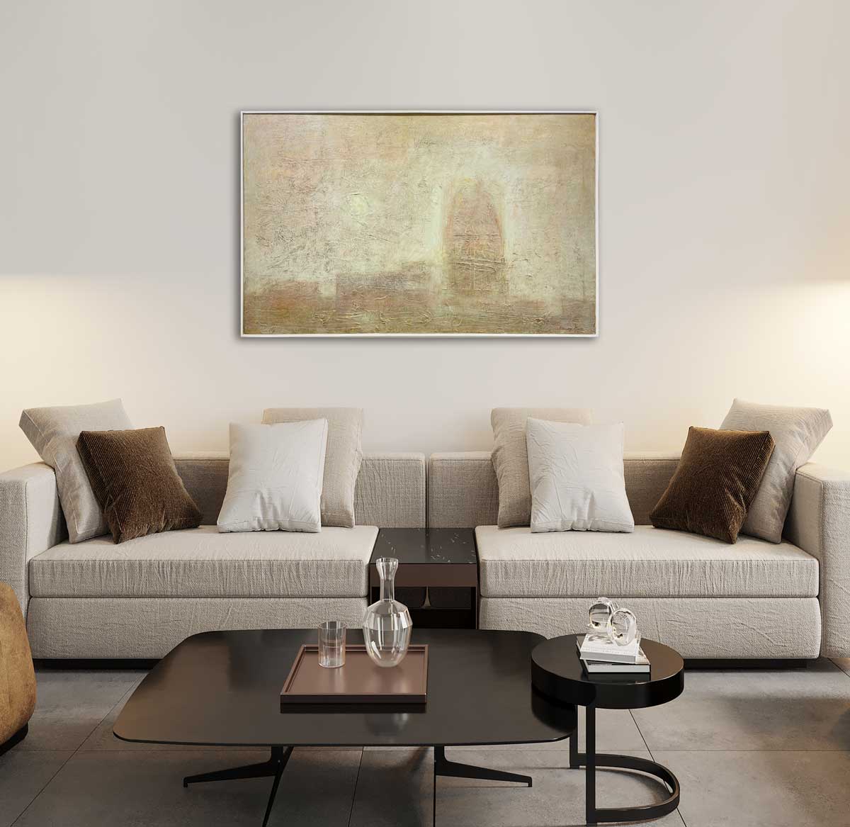 A beige abstract painting by Stanley Bate in a white floater frame hanging on a white wall above a light beige couch with brown throw pillows and a black metal coffee table all on a tile floor.