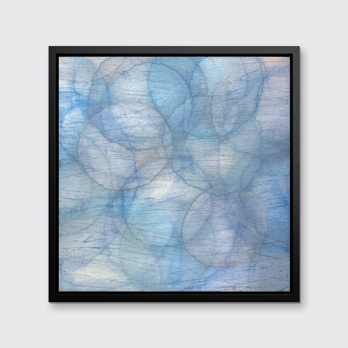 A blue and light blue abstract overlapping circle print in a black floater frame hangs on a white wall.