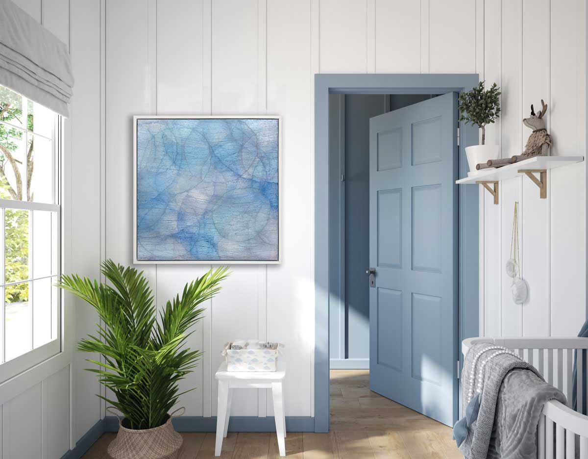 Layers of overlapping circles with an iridescent feel in blues, light purples and light greens staged in a white floater frame on a wall in a nursery.