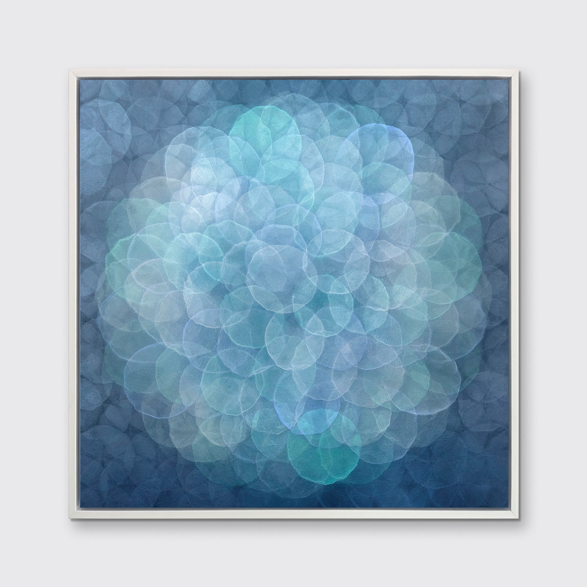 A blue, teal, light lavender and white abstract geometric print in a white floater frame hangs on a white wall.