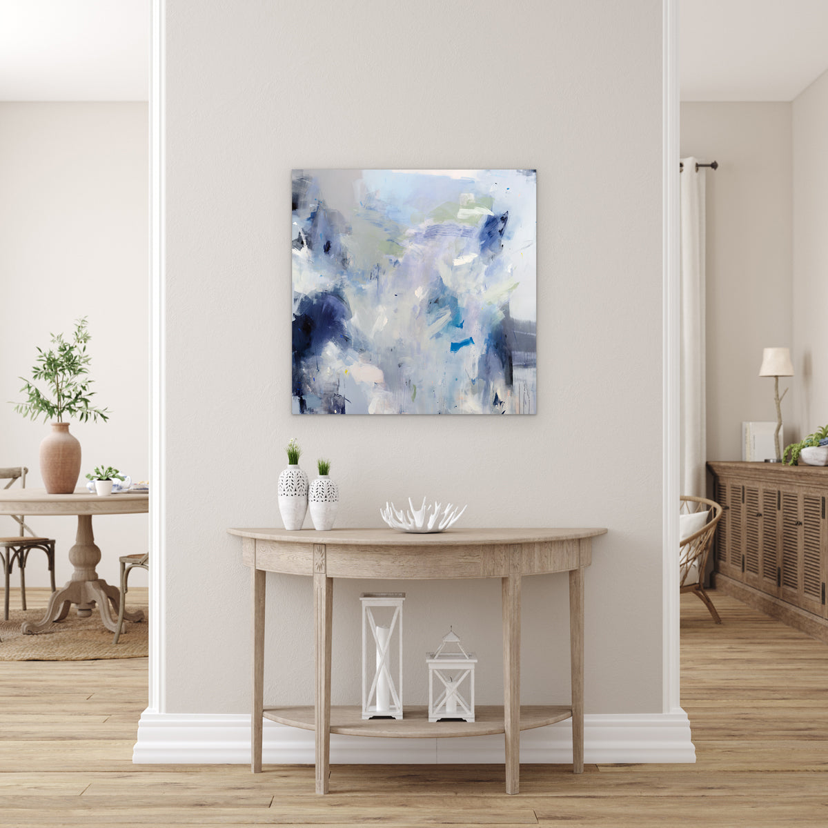 An abstract painting by Kelly Rossetti featuring blue, white and green brushstrokes is hung above a table..