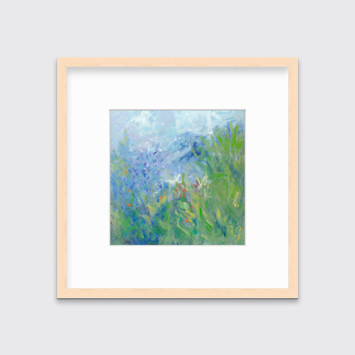 A blue, green, yellow and white abstract floral print in a natural wood frame with a mat hangs on a white wall.