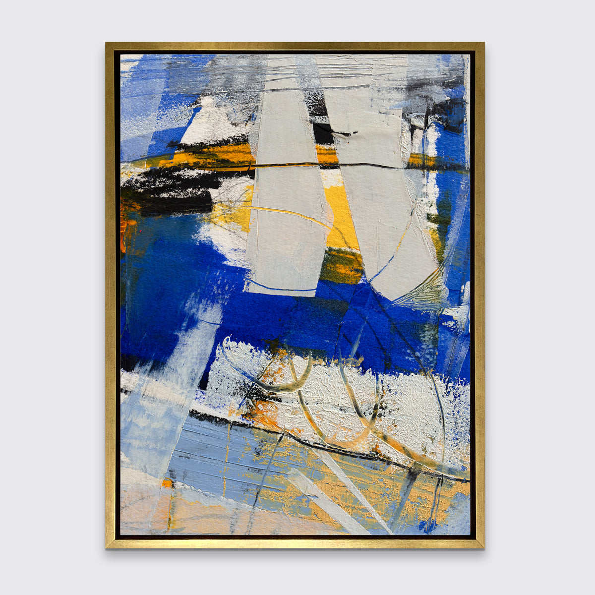 A blue, grey and yellow abstract print in a gold floater frame hangs on a white wall.