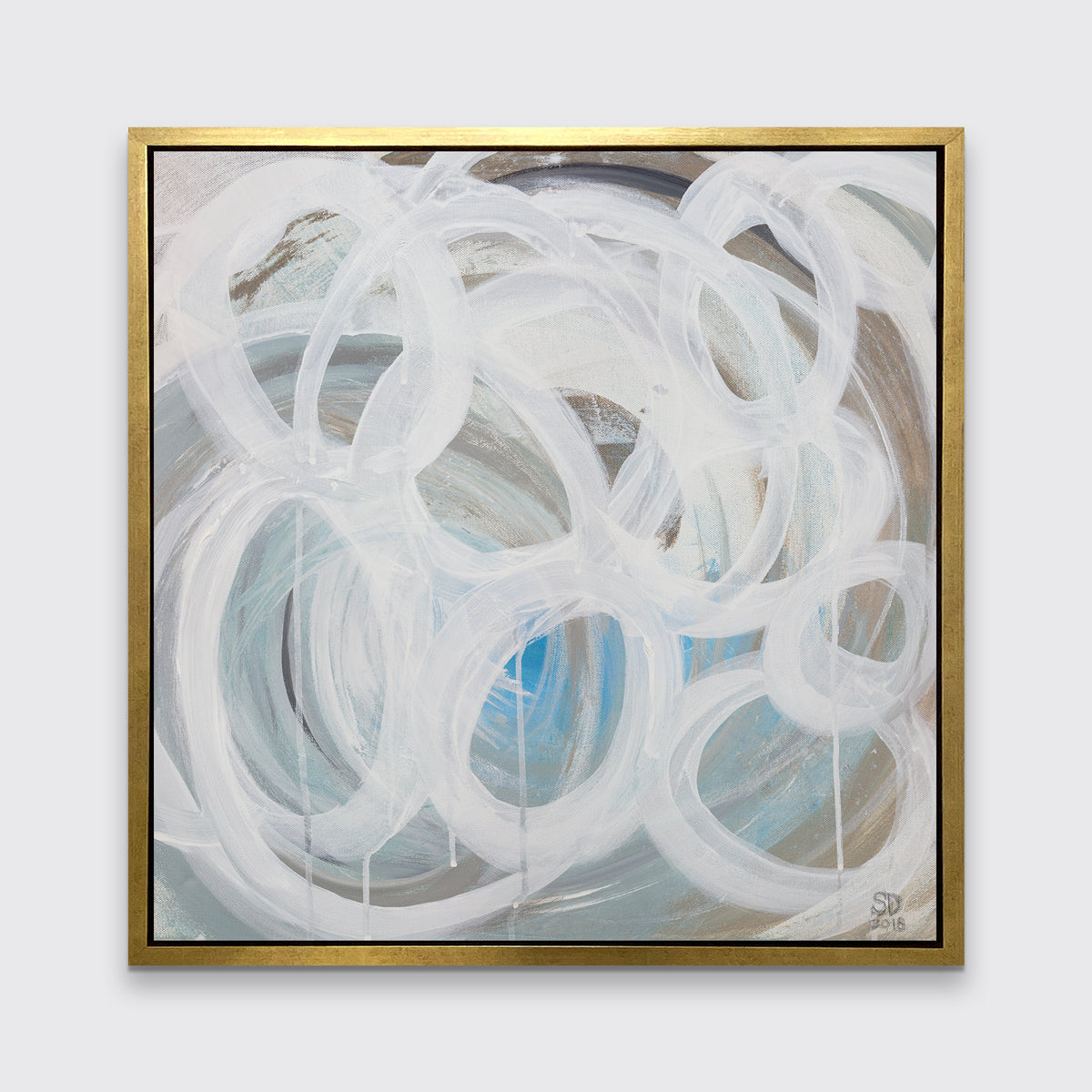 A white, light teal, blue and beige abstract print in a gold floater frame hangs on a white wall.