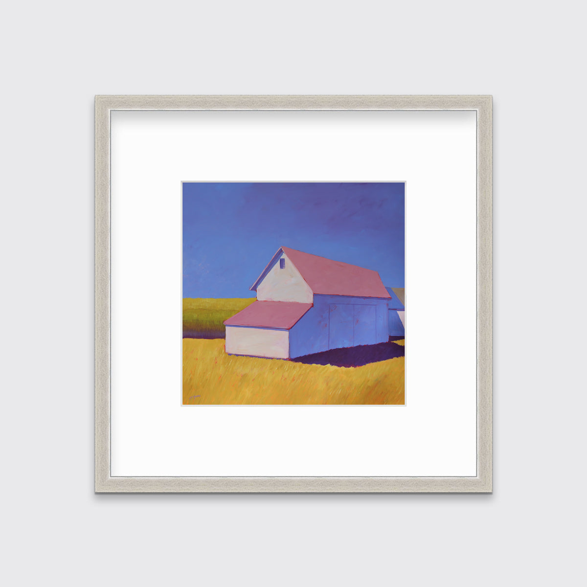 A white barn with a pink roof and yellow grass print in a silver frame with a mat hangs on a white wall.