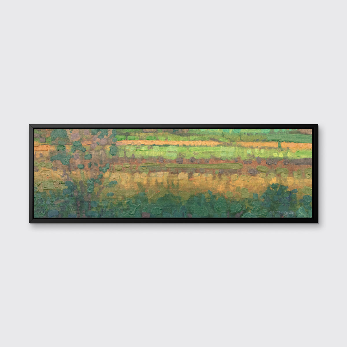 A green, yellow and deep orange abstract landscape print in a black floater frame hangs on a white wall.