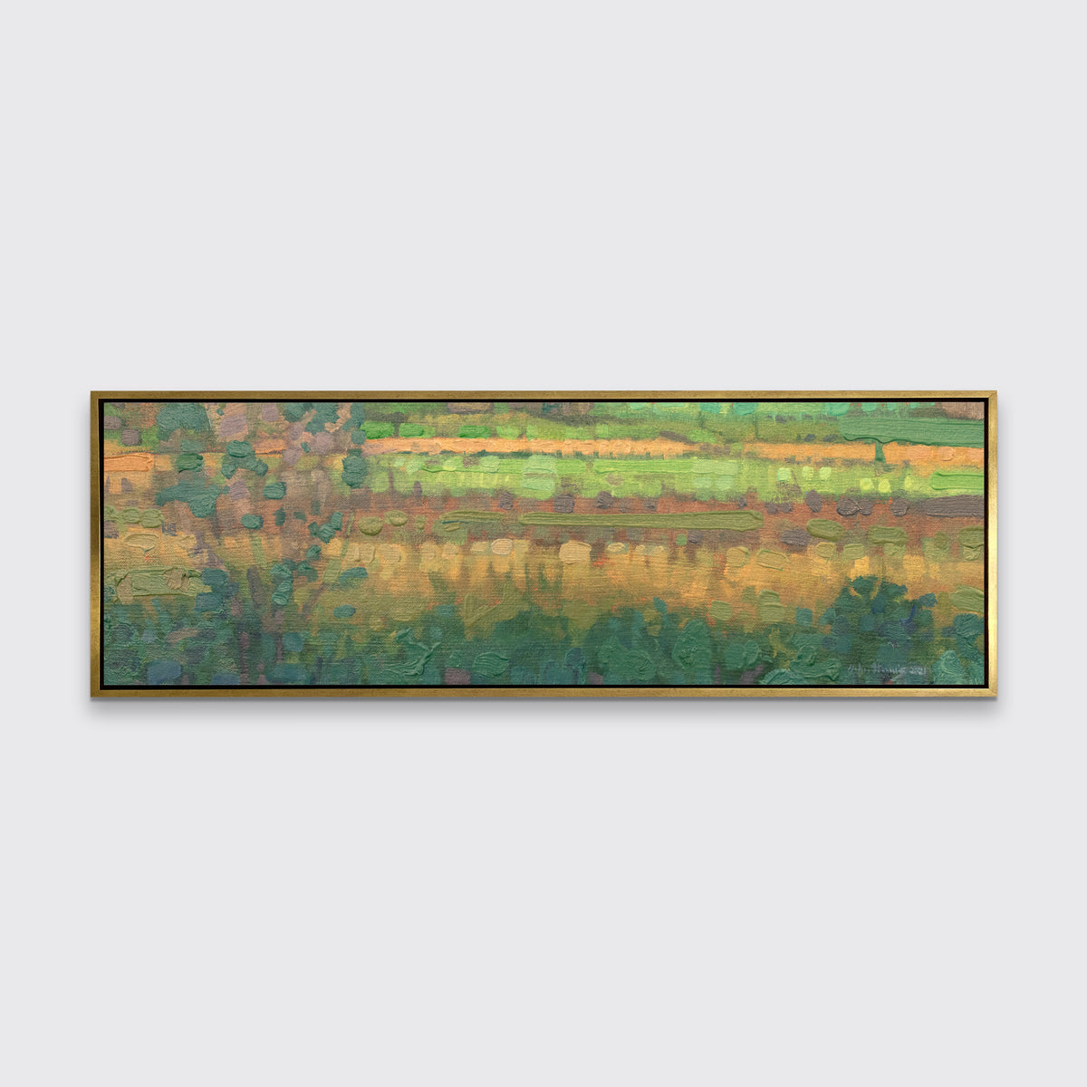 A green, yellow and deep orange abstract landscape print in a gold floater frame hangs on a white wall.