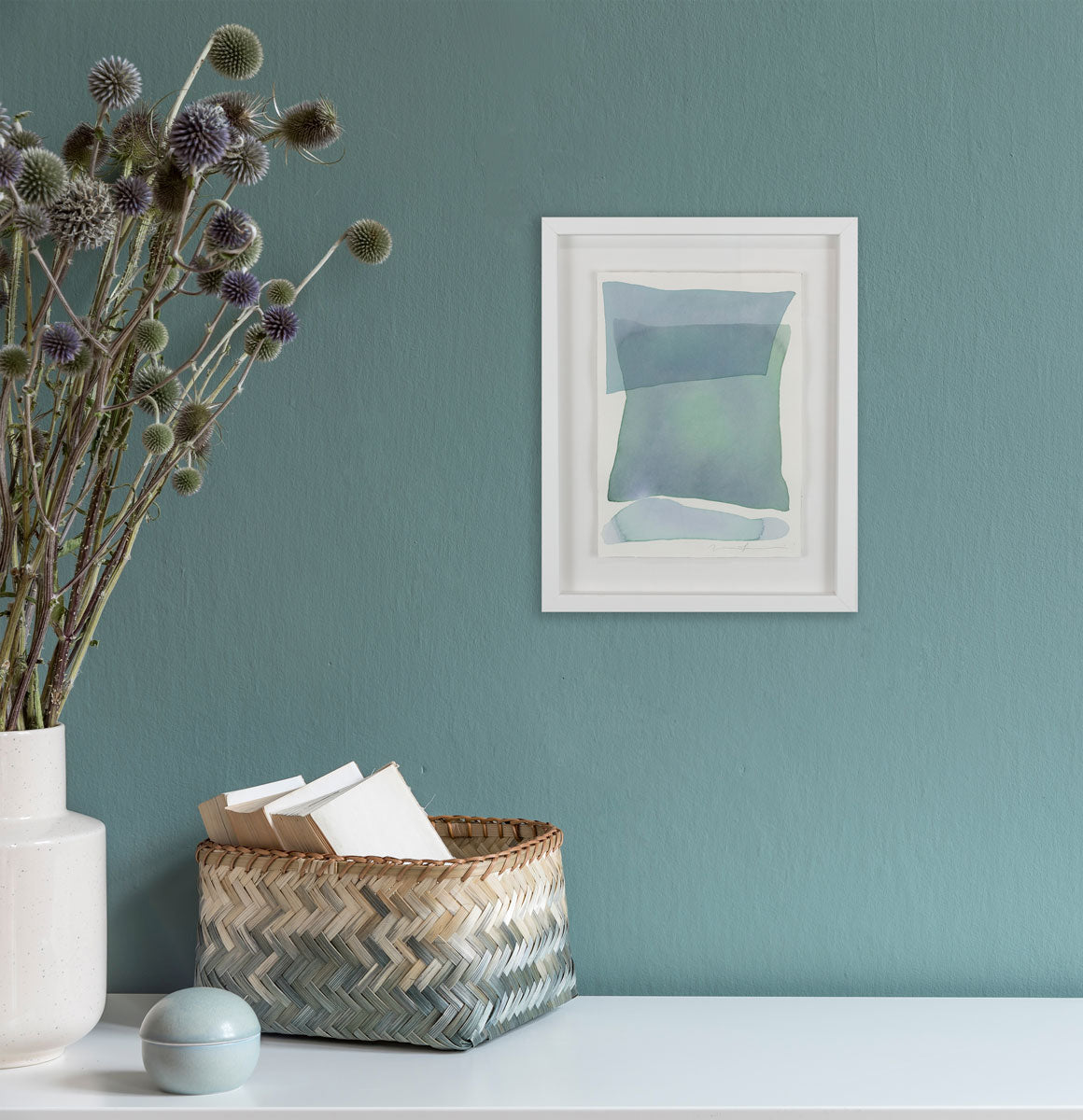 A watercolor painting of blue and turquoise stacked forms hung above a dresser. Wired and ready to hang.