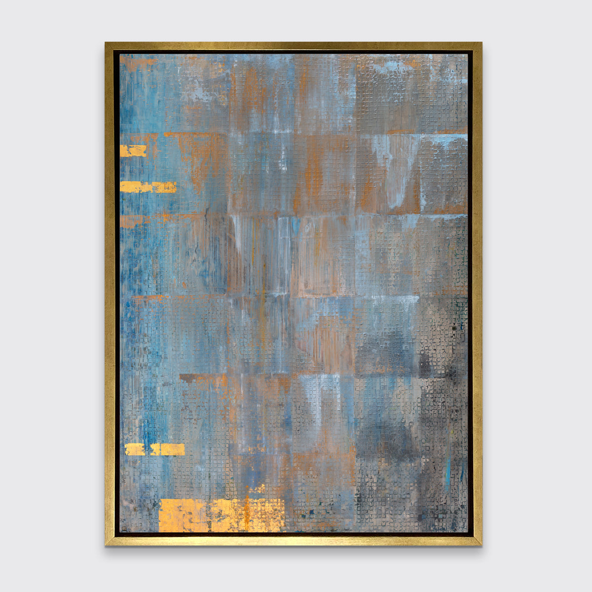A blue, grey and gold abstract geometric print in a gold floater frame hangs on a white wall.