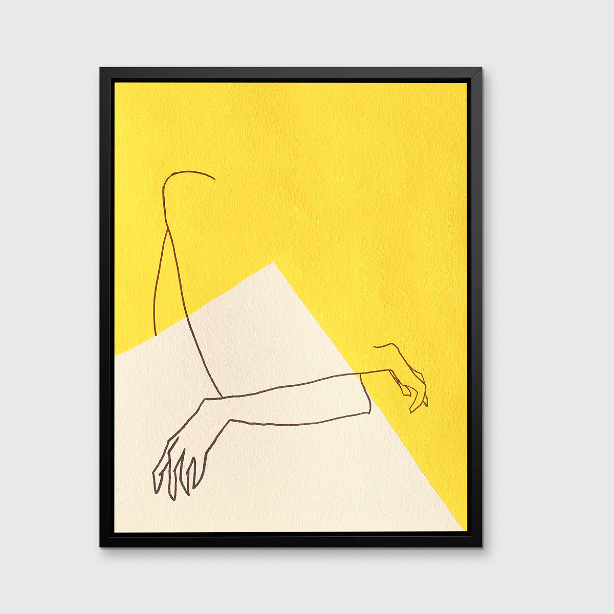 A yellow and white abstract print by Hazal Ozturk in a black floater frame hangs on a white wall.