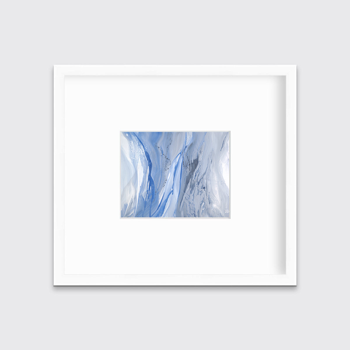 A blue, white and grey abstract print in a white frame with a mat hangs on a white wall.