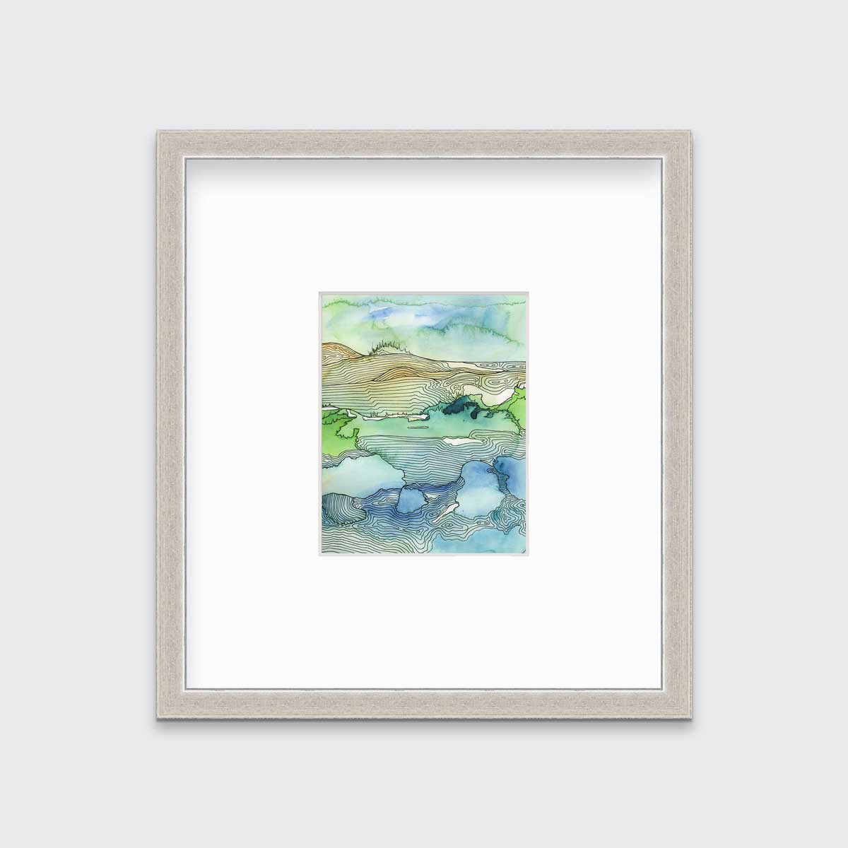 A green and blue landscape illustration print framed in a silver frame with a mat hangs on a light grey wall.