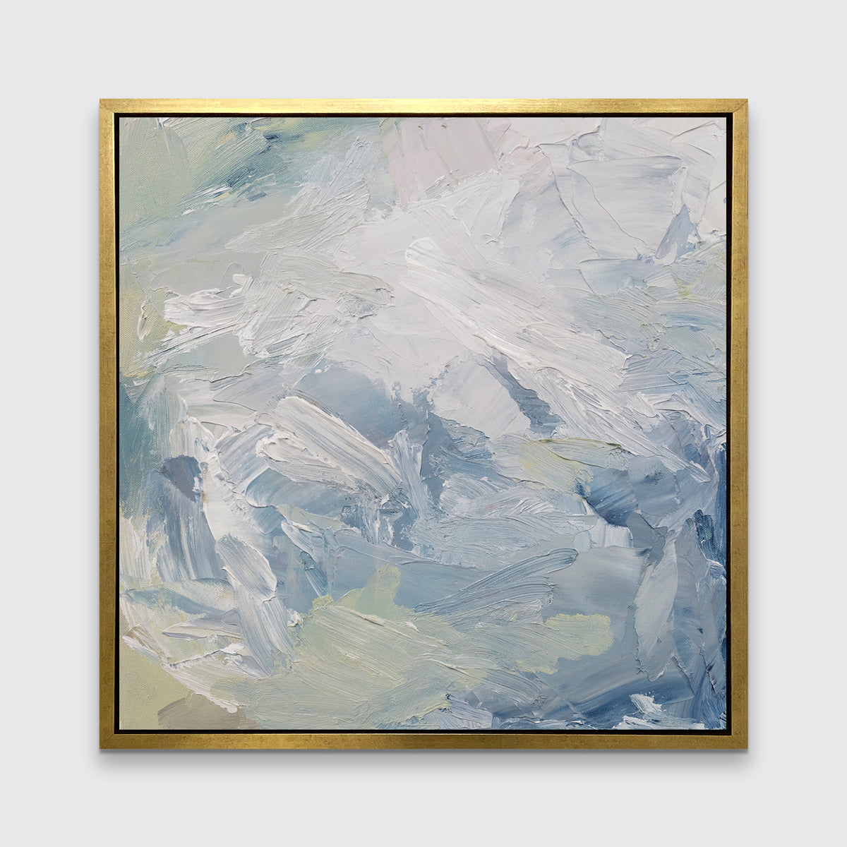 A white, blue, grey and light green abstract print in a gold floater frame hangs on a white wall.