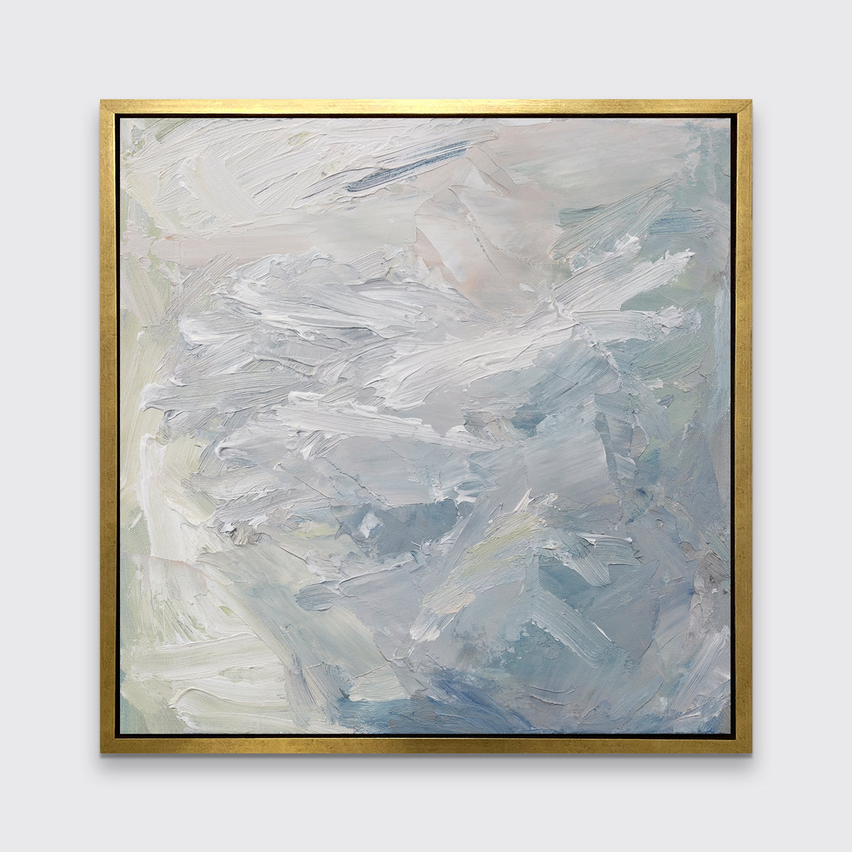 A white, blue, grey and light green abstract print in a gold floater frame hangs on a white wall.