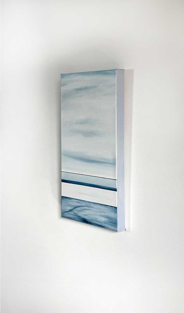 A right side-angle view of a blue and white abstract painting hanging on a white wall.