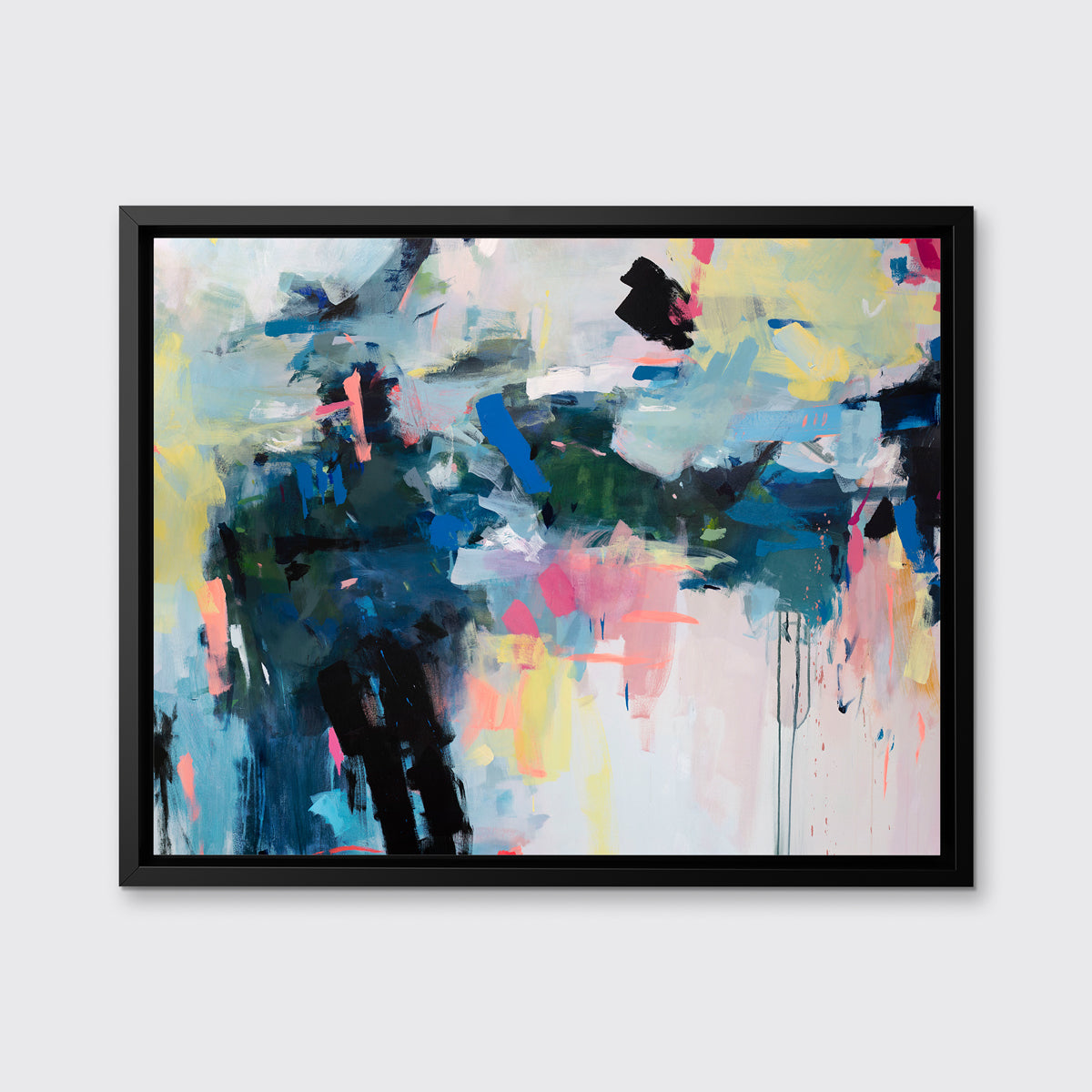 A multicolored abstract print in a black floater frame hangs on a white wall.
