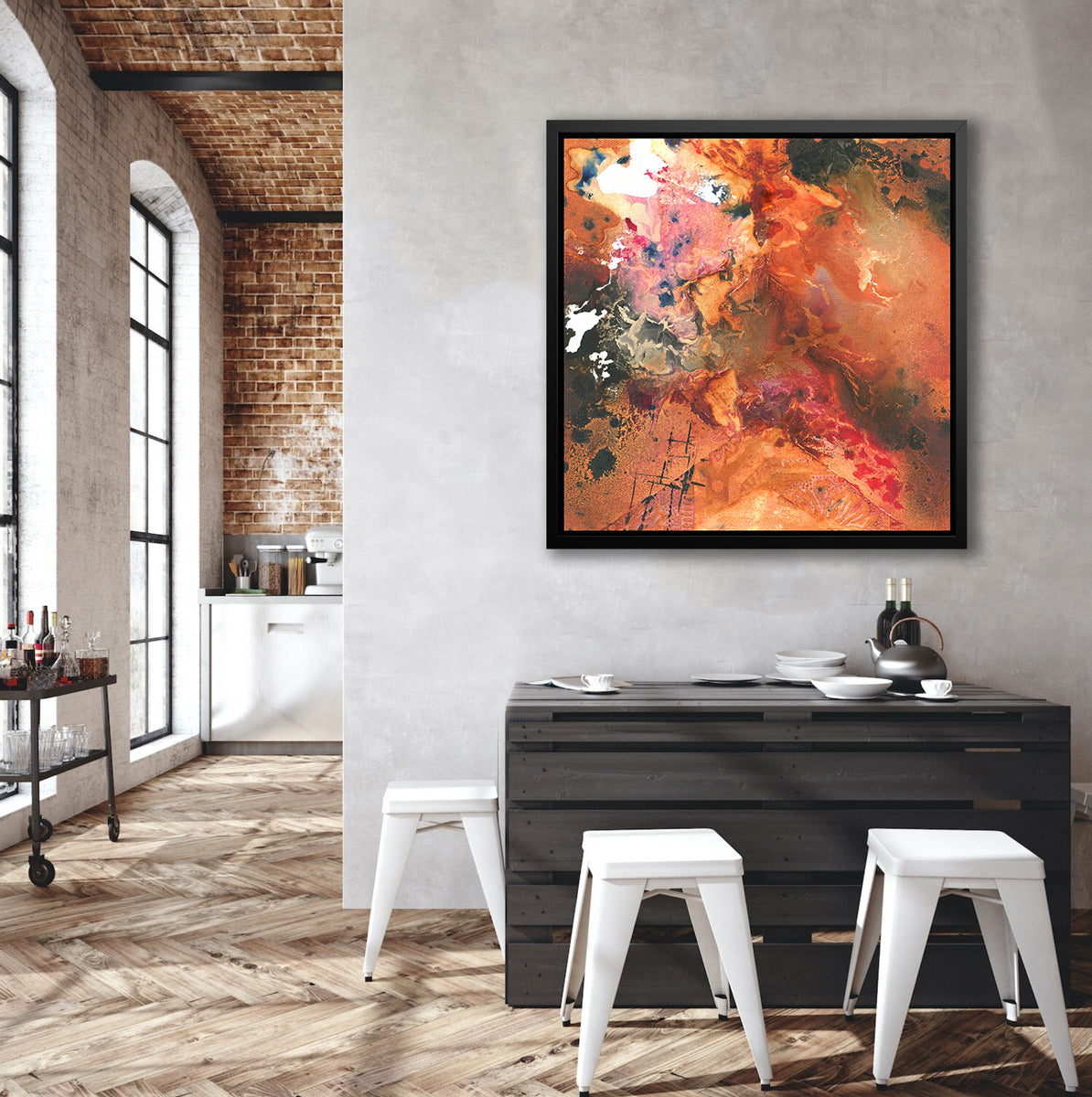 A red, orange, black and pink abstract print in a black floater frame hangs on a grey wall above a black palette table with three white stools surrounding and next to an opening to a hallway with a full bar cart.