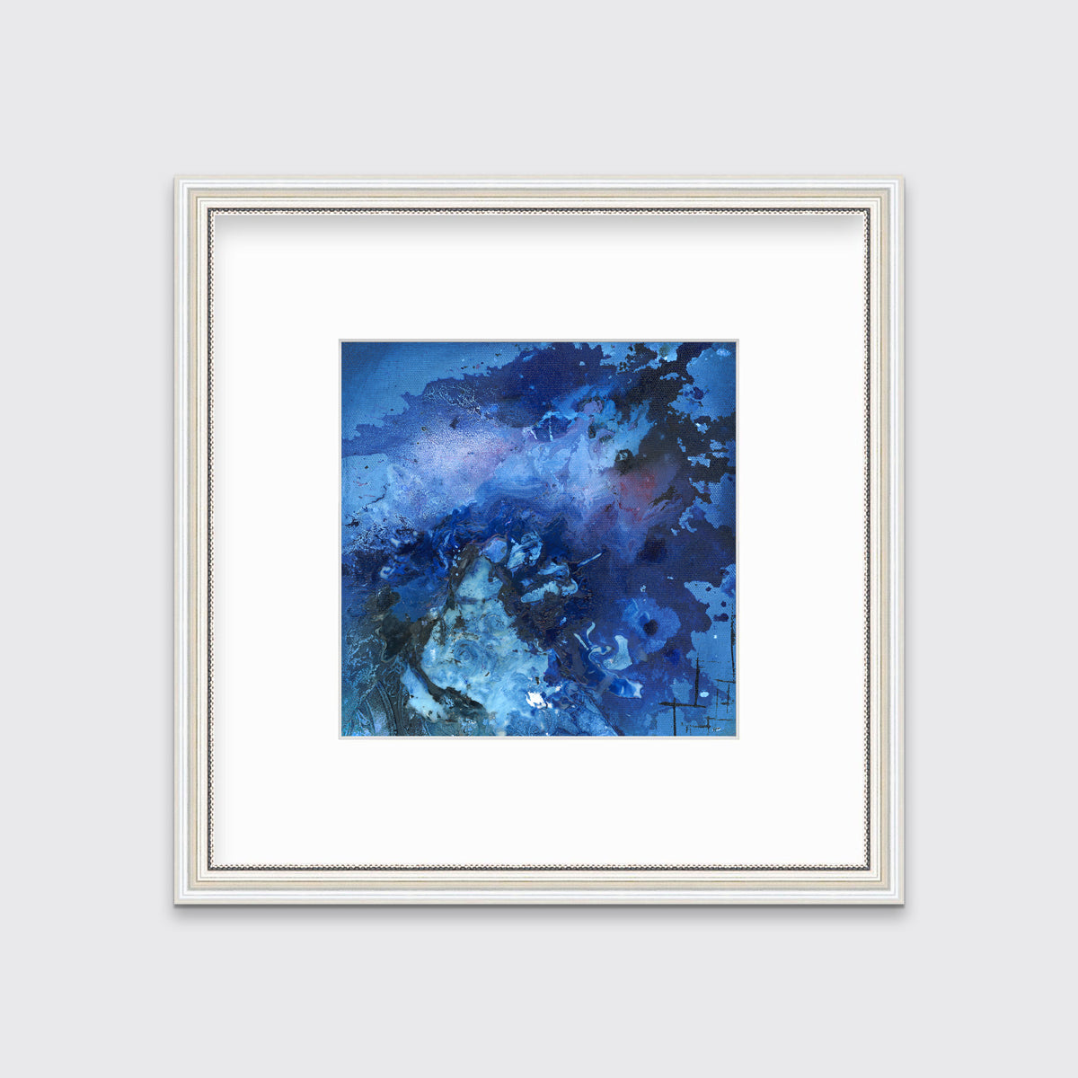 A blue and black abstract print in a white frame with antiqued beading with a mat hangs on a white wall.