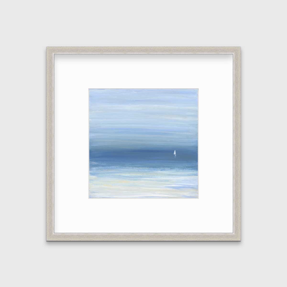 A blue, beige and white abstract seascape print with a small sailboat in a silver frame with a mat hangs on a white wall.