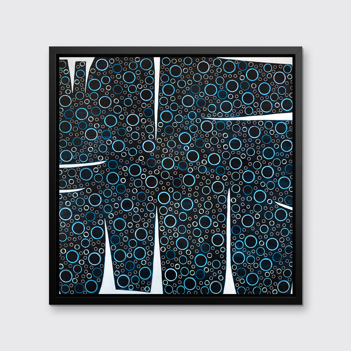 A black, blue and white abstract print in a black floater frame hangs on a white wall.