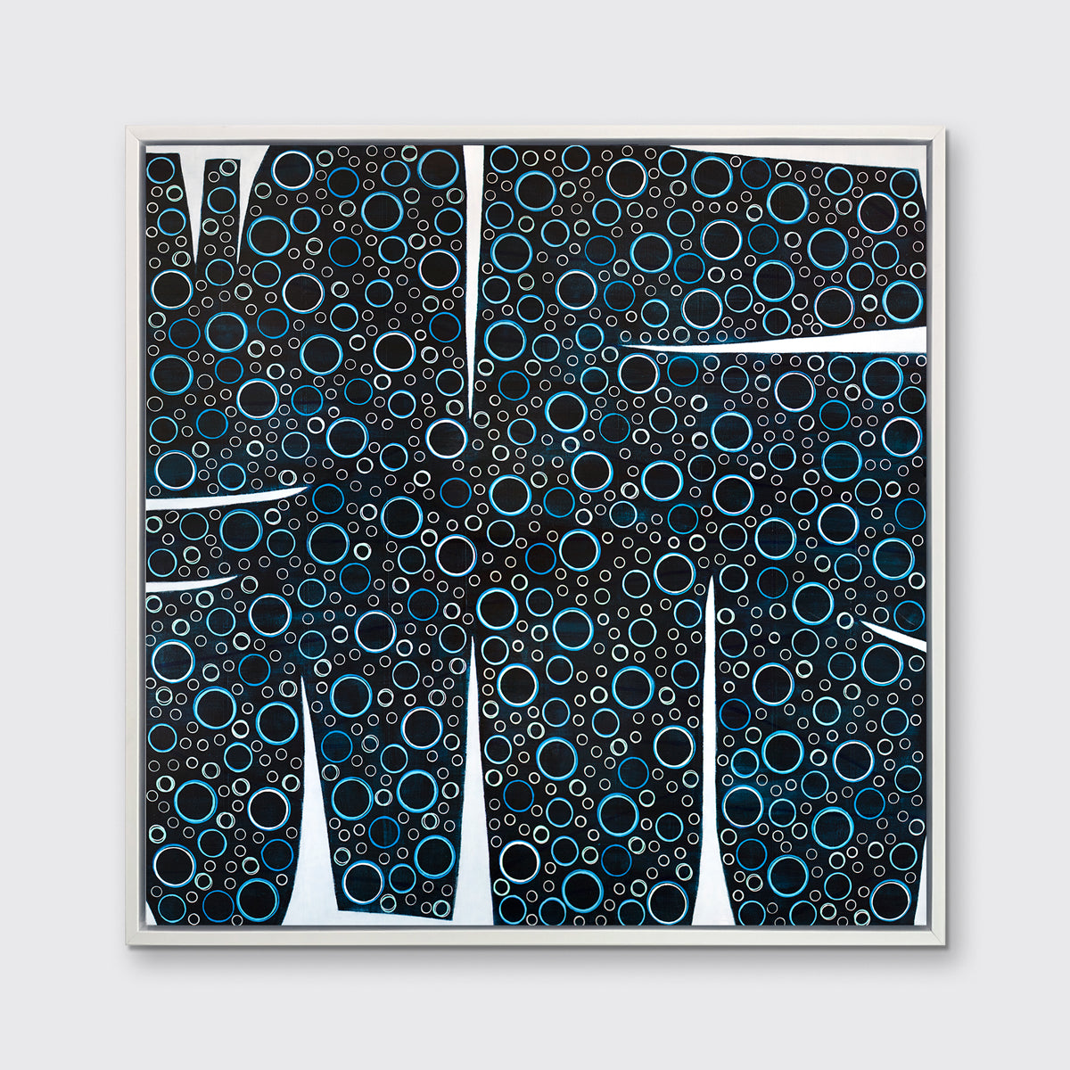 A black, blue and white abstract print in a white floater frame hangs on a white wall.