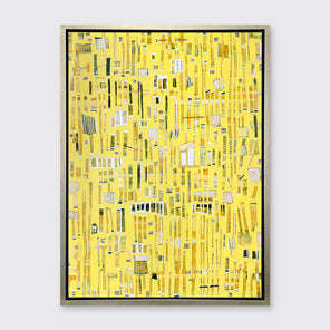 A yellow, white and black abstract print in a silver floater frame hangs on a white wall.