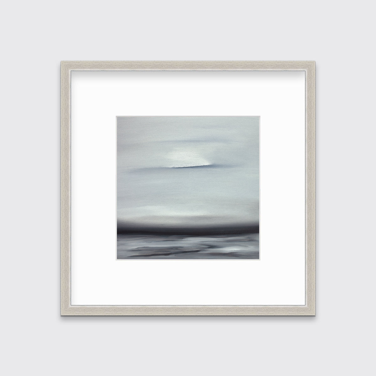 A tonal grey and black print in a silver frame with a mat hangs on a white wall.