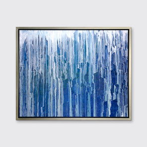 A blue and white abstract print in a silver floater frame hangs on a white wall.