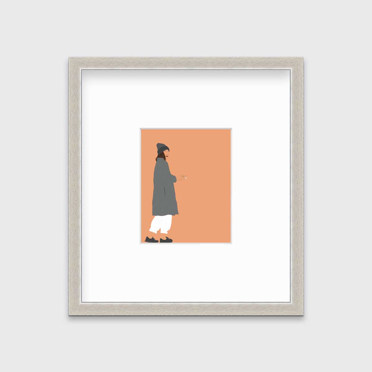 Art print of an illustrated woman wearing grey hat and coat, white pants, and grey sneakers, holding a cigarette with orange background, framed in a silver frame on a grey wall.