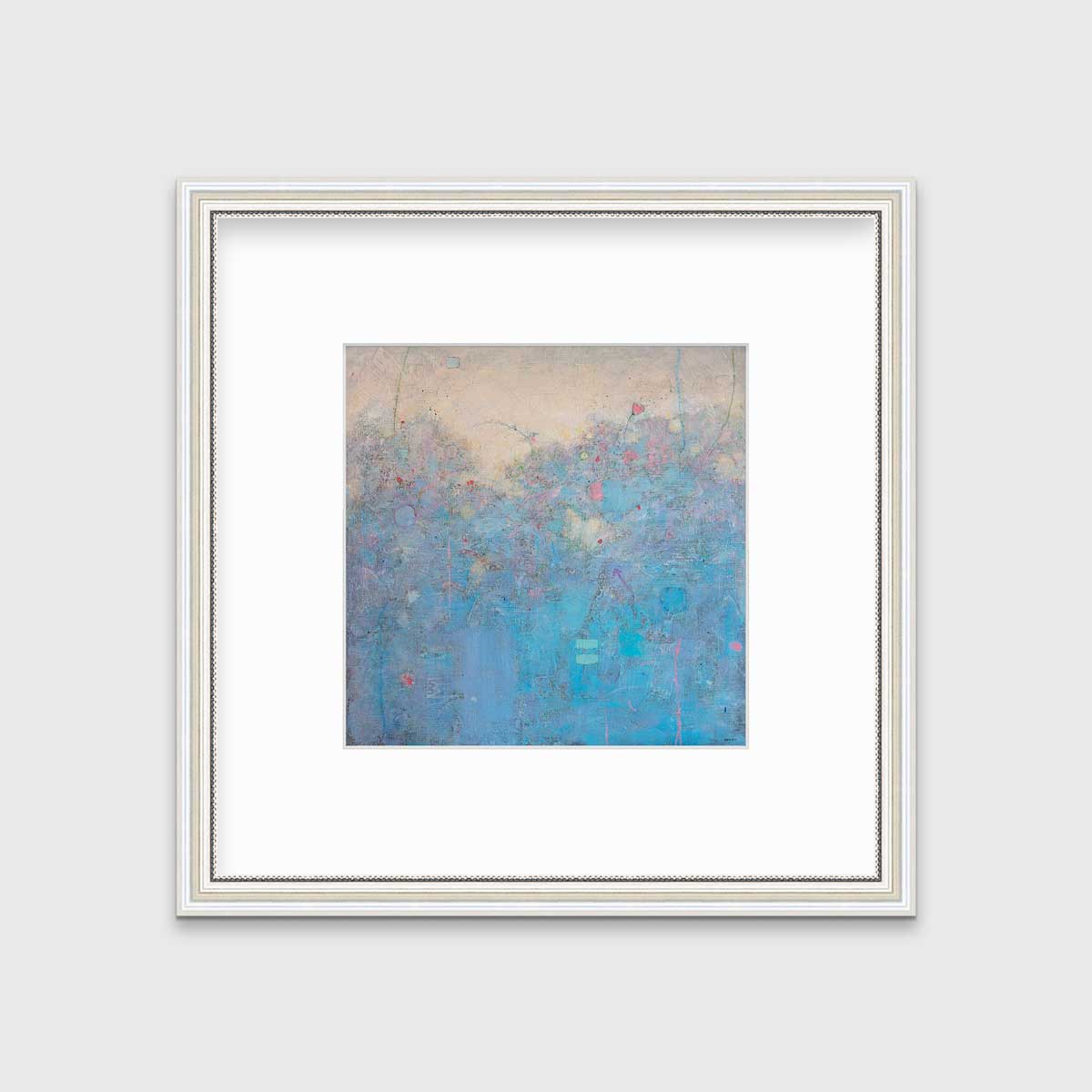 A blue abstract landscape print in a silver frame with antiqued beading with a mat hangs on a white wall.
