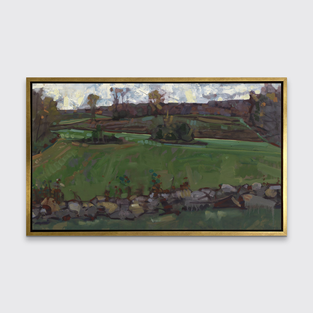 A green, brown and white abstract landscape print in a gold floater frame hangs on white wall.