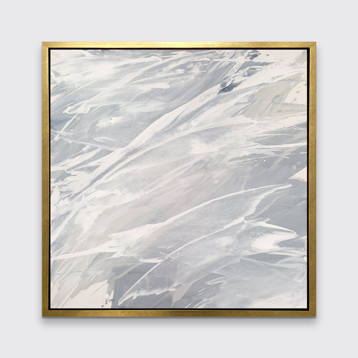 A grey, beige and white abstract print in a gold floater frame hangs on a white wall.