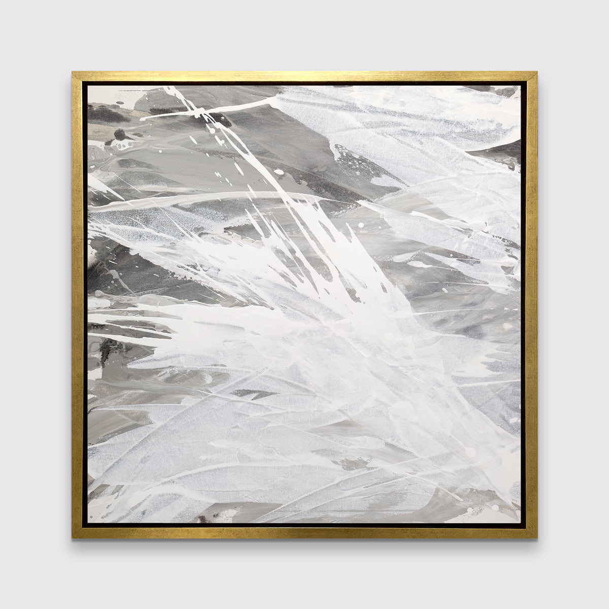 A grey, beige and white abstract print in a gold floater frame hangs on a white wall.