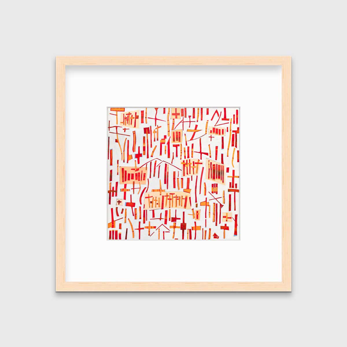A red, orange and white abstract print in a natural wood frame with a mat hangs on a white wall.
