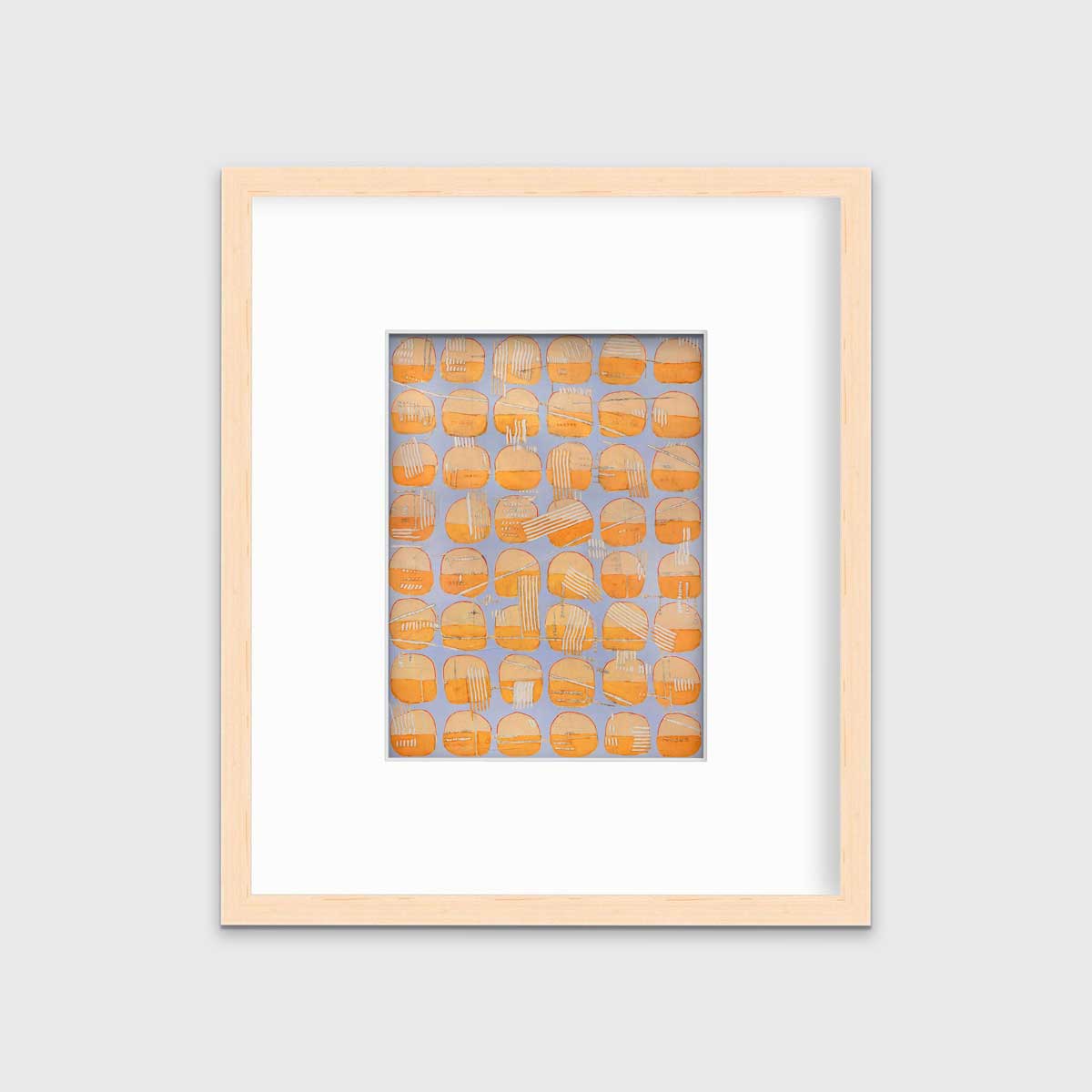 A orange and light purple abstract circle print in a natural wood frame with a mat hangs on a white wall.