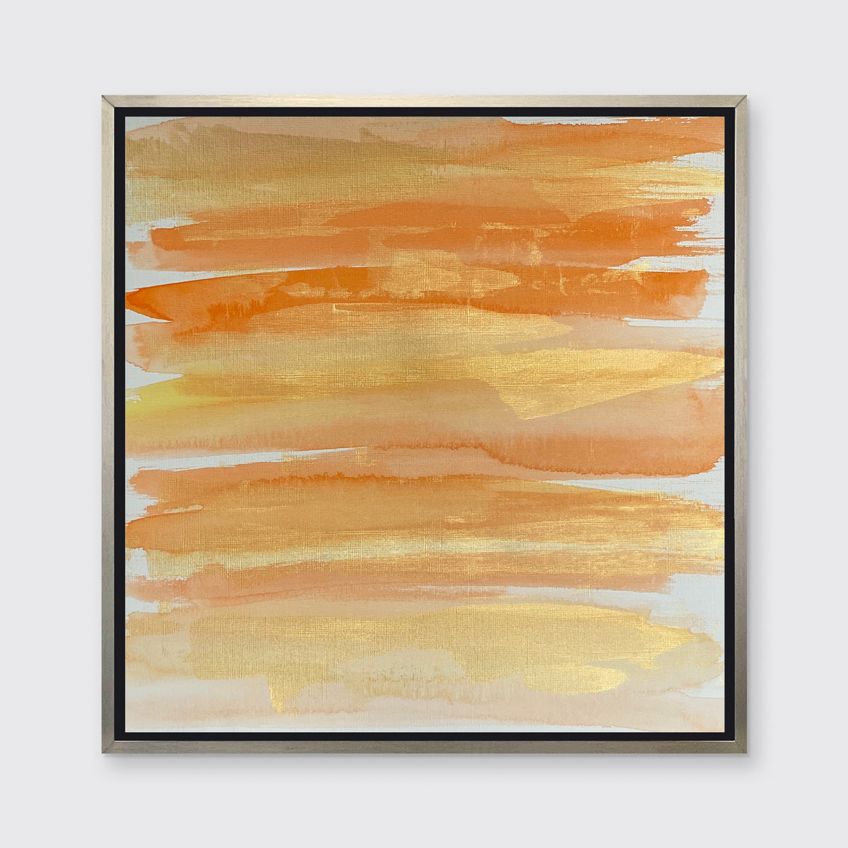 A orange, gold and white abstract print in a silver floater frame hangs on a white wall.